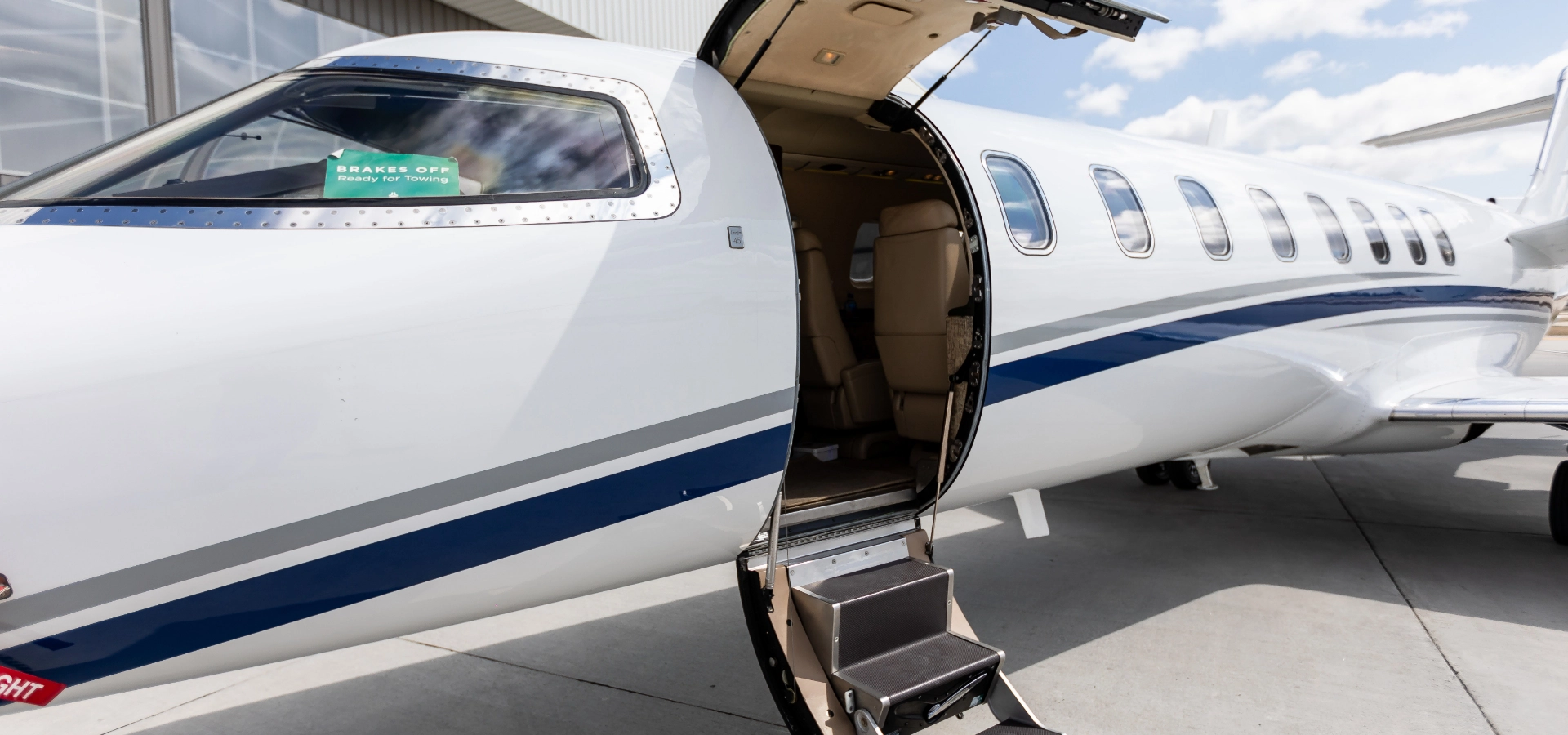 Private jet with an open door on a sunny day, steps inviting you aboard, offering a glimpse into the world of corporate jet sales.