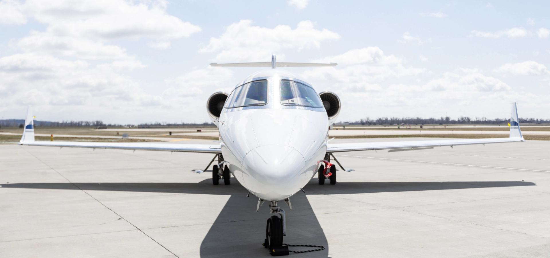 A white jet airplane, representing the pinnacle of aircraft acquisition, is parked on an airport runway under a cloudy sky.