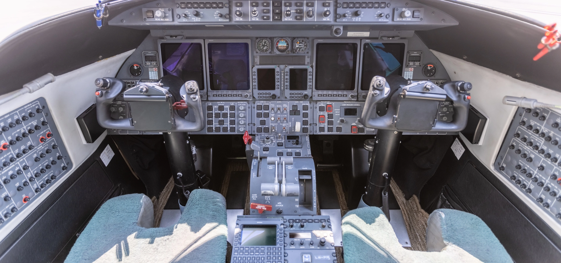 The cockpit of an aircraft features various control panels, screens, and state-of-the-art equipment, embodying the sophistication found in luxury jet sales. With two seats and a central control column, this space is designed for ultimate precision and comfort.