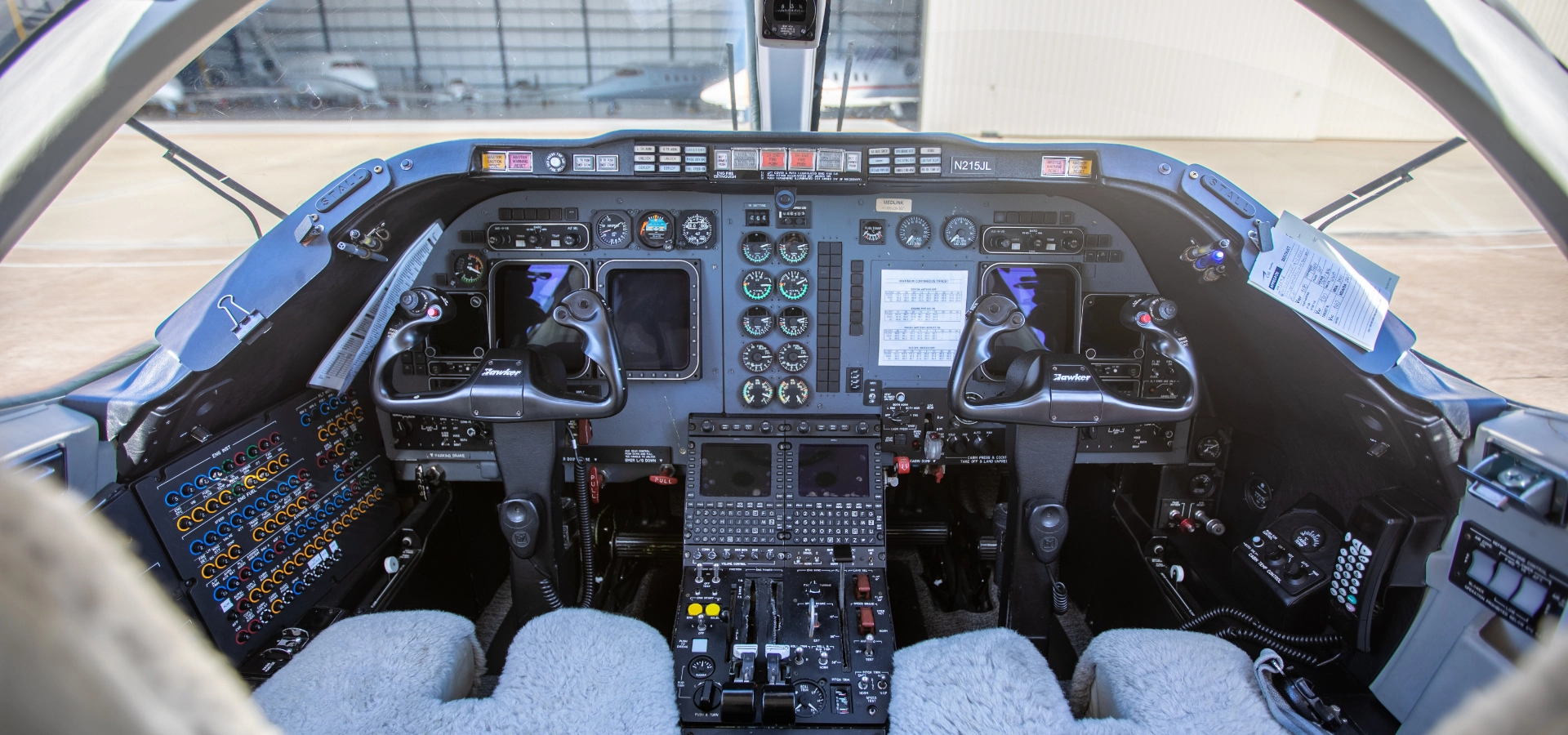 Cockpit of an aircraft showcasing various controls, instruments, and two pilot seats with sheepskin covers—a testament to meticulous aviation consulting services.