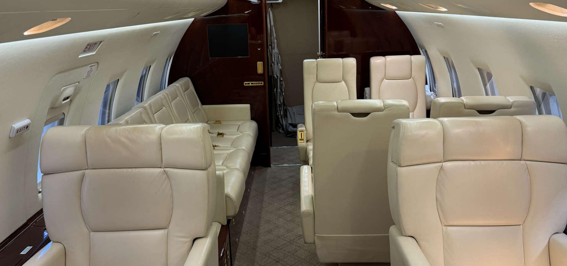 The interior of a private jet showcases cream-colored leather seats and elegant wood paneling, embodying the sophistication found in luxury jet sales.