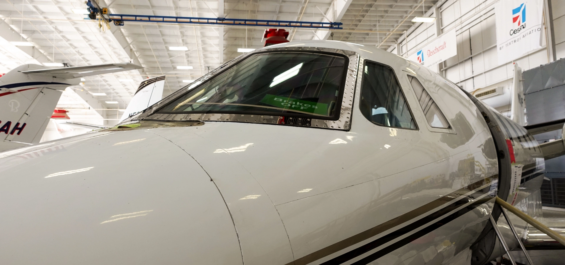 Close-up of a white airplane parked inside a hangar, showcasing its cockpit windows and part of the fuselage—a stunning example among luxury jet sales.