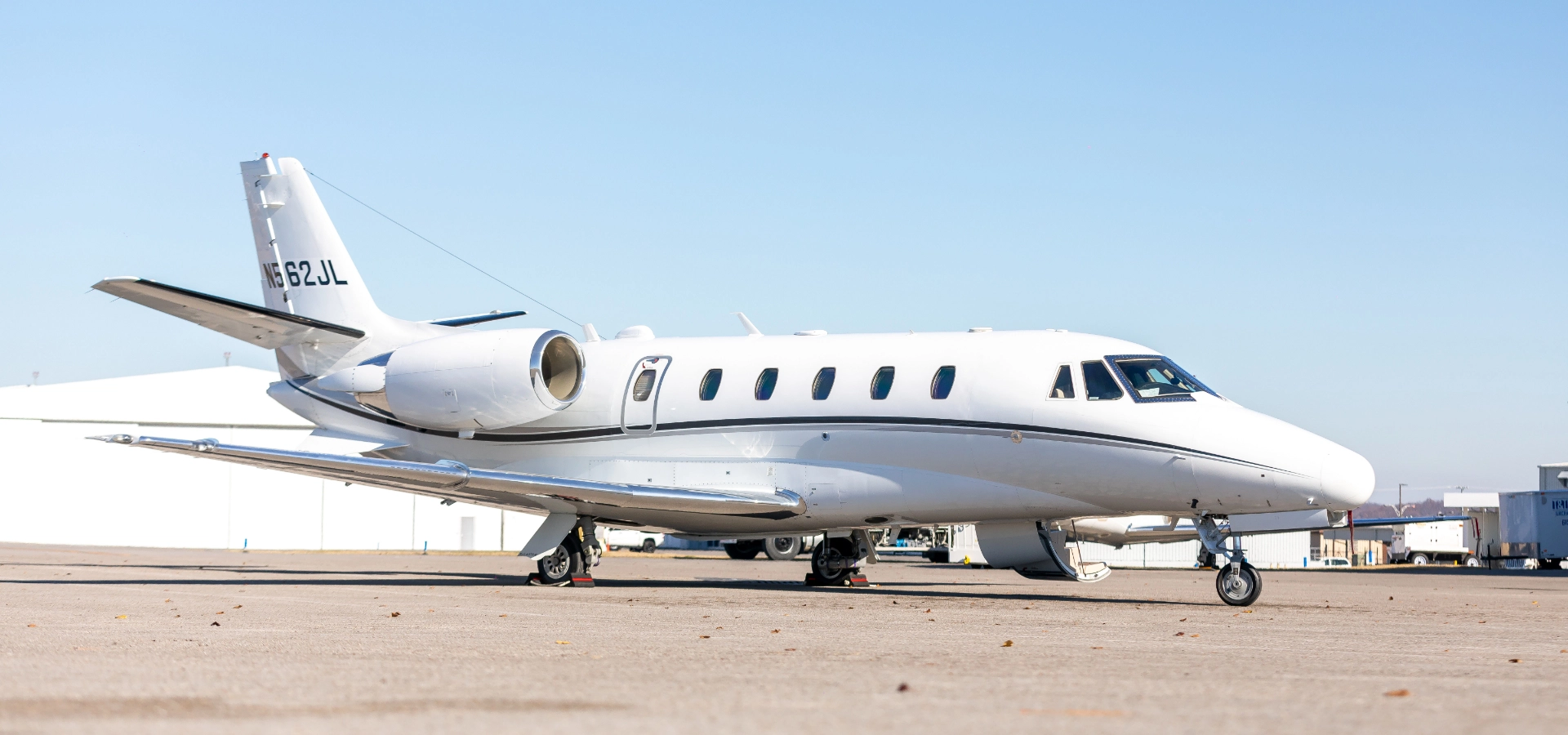 A sleek white private jet, ideal for aircraft acquisition, is parked gracefully on an airport tarmac beneath a clear blue sky.