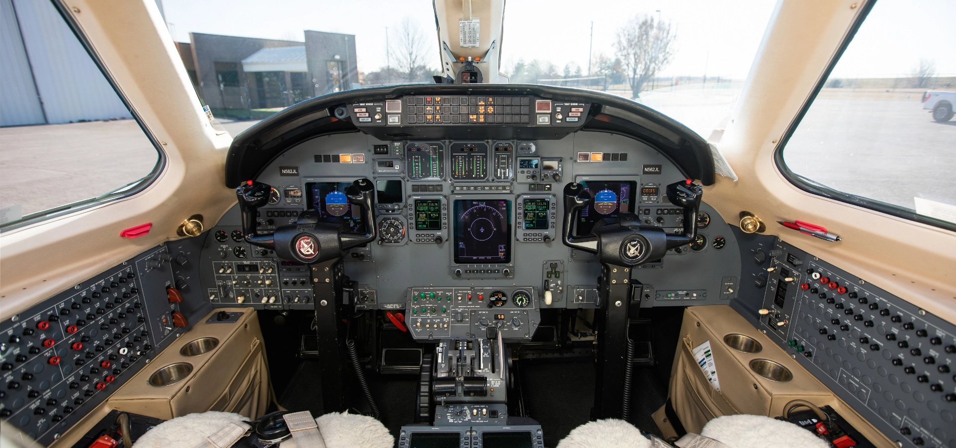 Explore the cockpit interior of a business jet for sale, featuring multiple control panels, screens, switches, and seating for two pilots.