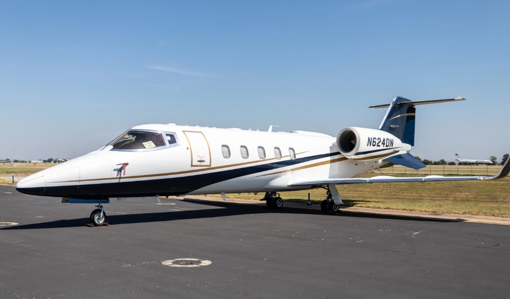 A sleek white and blue private jet, symbolizing the apex of luxury jet sales, sits elegantly on the airport tarmac against the backdrop of clear skies.