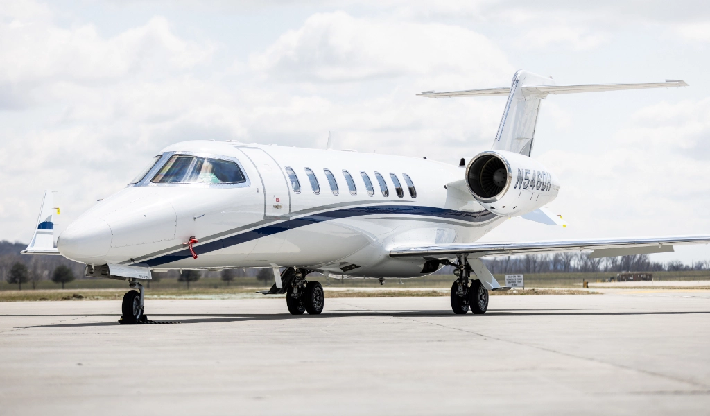 A luxury jet, perhaps part of a private jets for sale collection, is parked on an airport runway under a cloudy sky.
