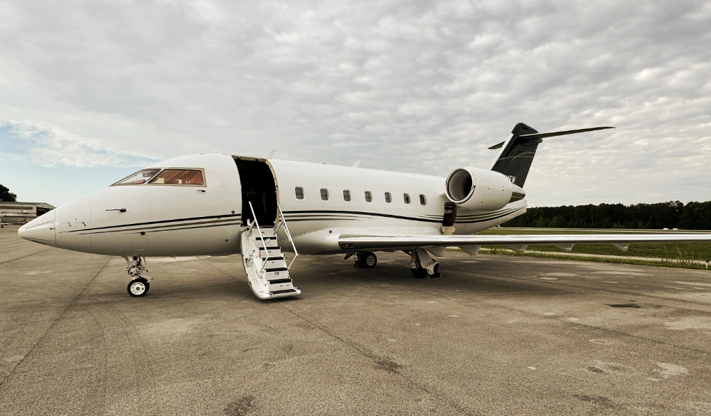 A small private jet is parked on an airport tarmac, its door open and stairs gracefully extended, awaiting passengers.