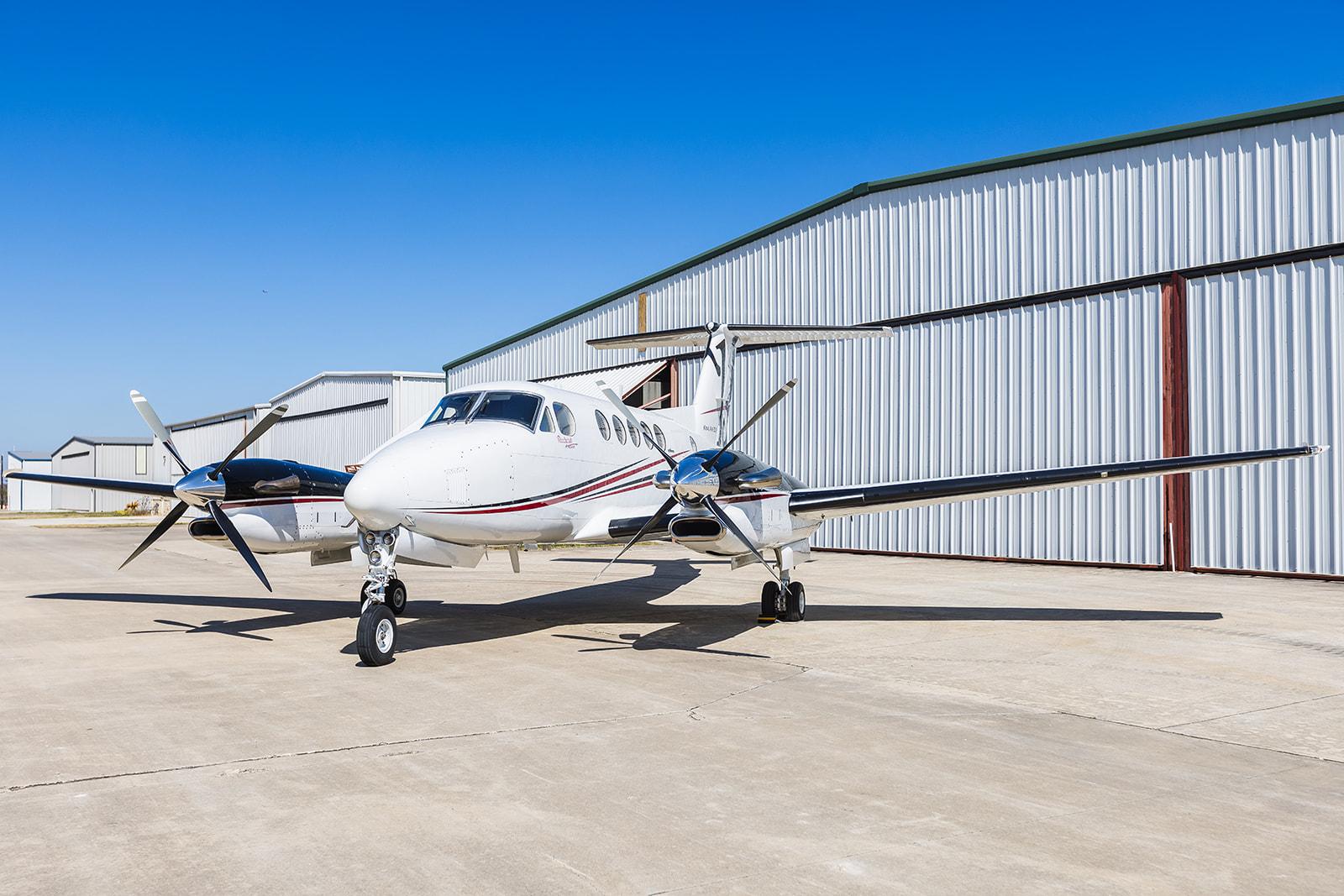 Matterhorn White with Black Velvet Metallic, Deep Red and Las Vegas Gold epitomizing luxury jet sales is parked on an airfield under a clear blue sky.